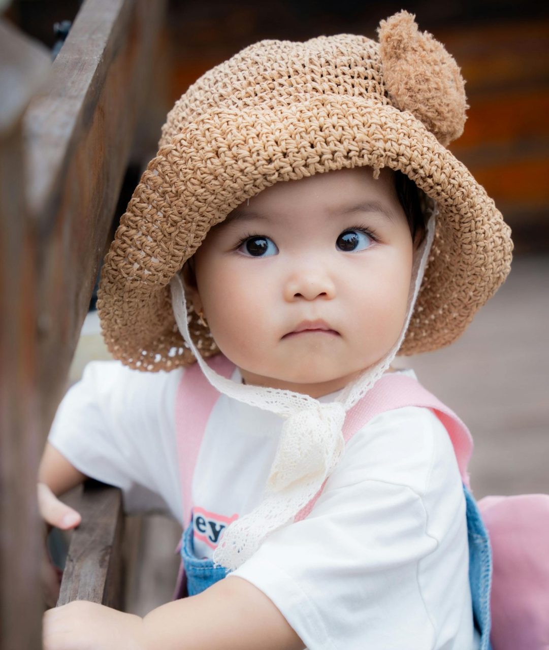 Charming portrait of a baby girl in a straw hat outdoors in Ho Chi Minh City.